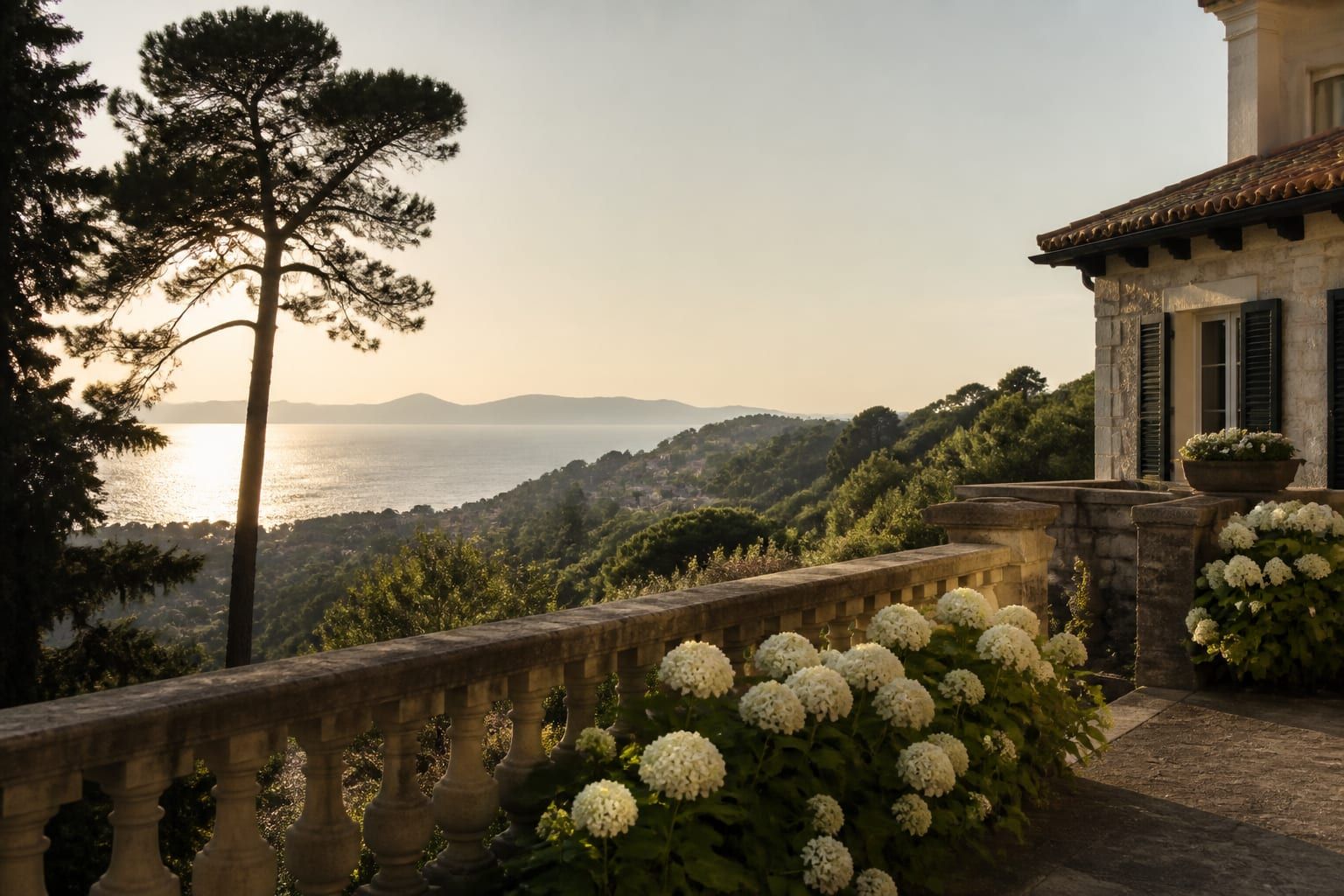 A villa terrace in the hills above Biarritz with hydrangeas and a view of the sea